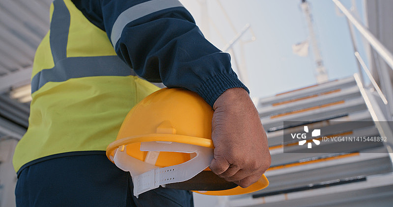 建筑、船舶技工或工程师手持安全帽特写。工业建筑工人在工作场所戴着黄色安全帽。图片素材