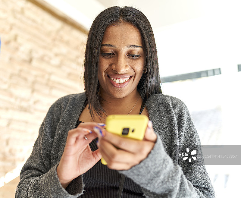 查看手机社交网络时看起来很有趣的年轻黑发女人图片素材