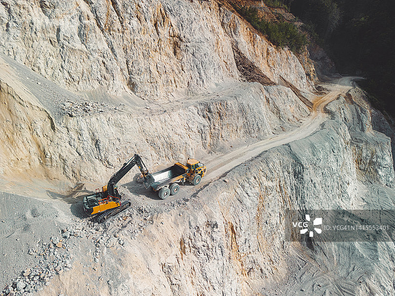 挖掘机将砾石装载到自卸卡车上图片素材