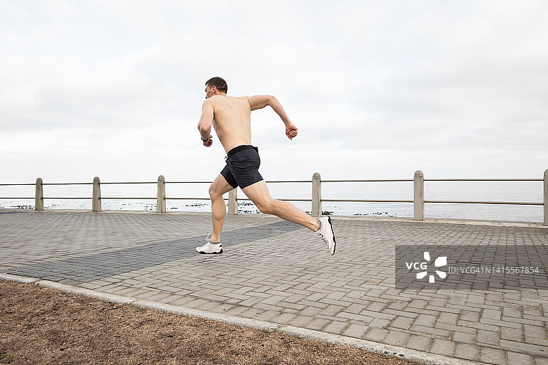 在木板路上跑步的健壮男人图片素材
