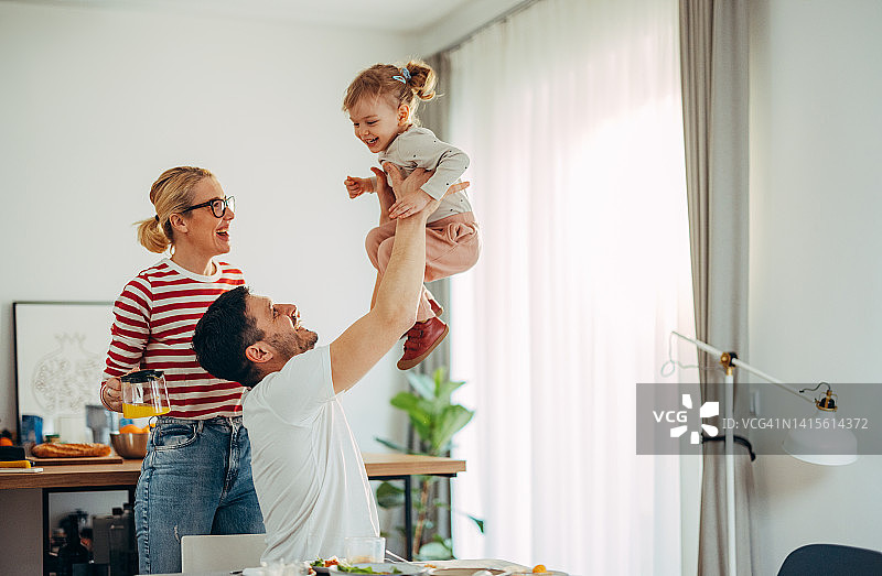 早餐时的乐趣：幸福的三口之家在家拥抱和互动图片素材