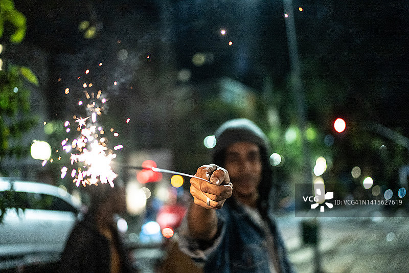 年轻男人夜晚街头燃放烟花庆祝图片素材
