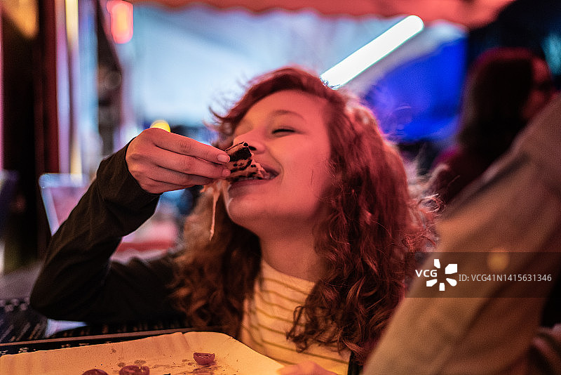 在户外夜晚吃披萨的年轻女人图片素材