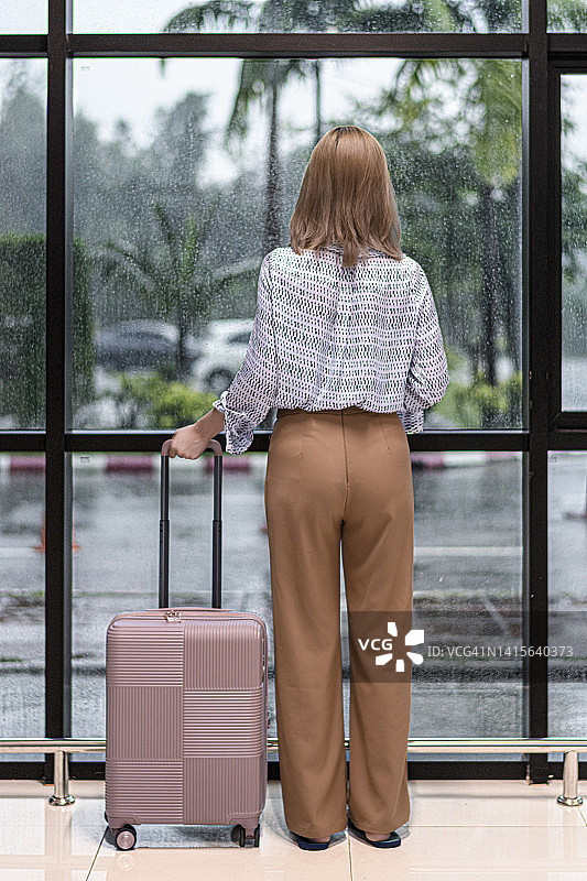 年轻女子在机场透过窗户向外看图片素材