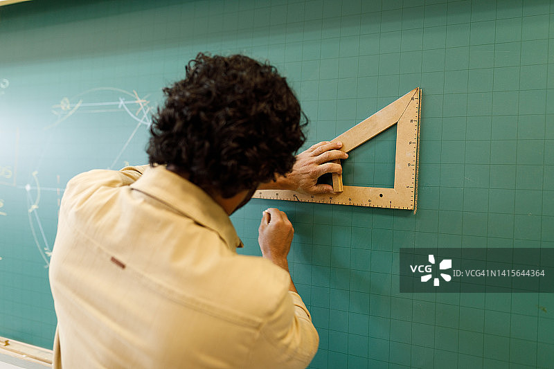 老师用木制三角板在黑板上画图图片素材