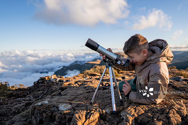 年轻探险家在山上用望远镜观察图片素材