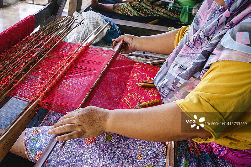在印度尼西亚传统织布机上工作的亚洲穆斯林妇女图片素材