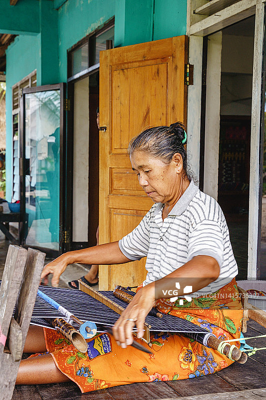 年长的亚洲妇女制作手工彩色传统纱笼图片素材