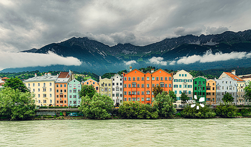 因斯布鲁克茵河沿岸的彩色排屋，远处可见暴风雨天气下的欧洲阿尔卑斯山图片素材
