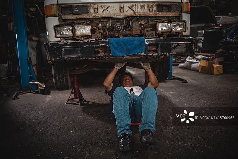 年长的机械师在车底使用工具图片素材