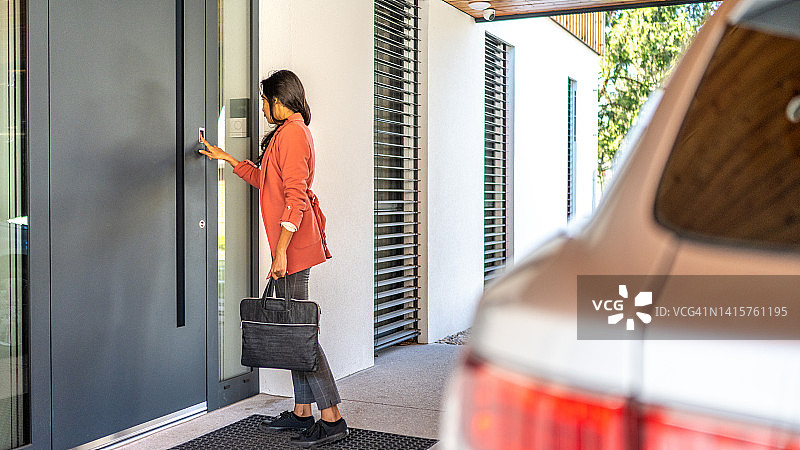 女人用手指按指纹扫描仪进入她的房子图片素材