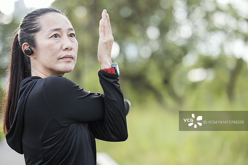 缓解肩部疼痛和僵硬的伸展运动。健康的成熟女运动员在城市公园户外跑步后，通过交叉肩部伸展进行放松。图片素材