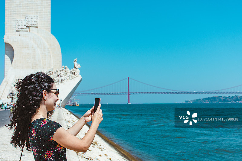 游客在特茹河边使用手机的背影图片素材