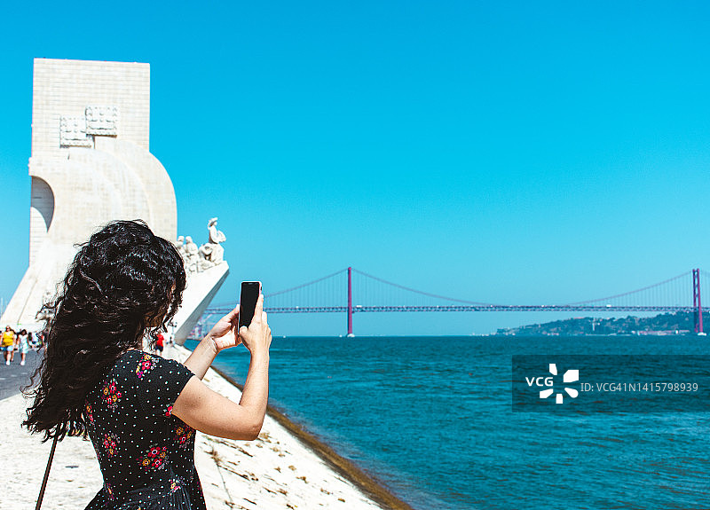 游客在特茹河边使用手机的背影图片素材