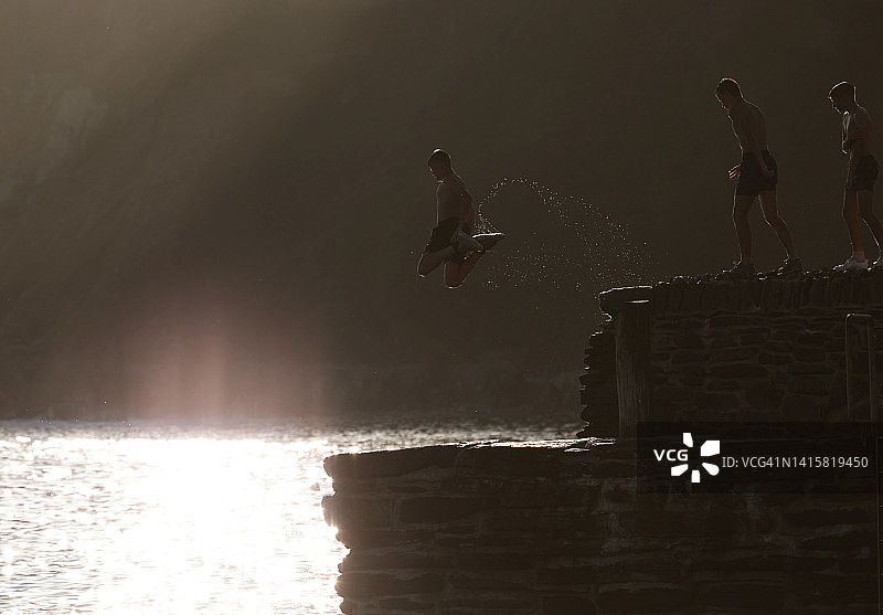在康沃尔郡海港墙上跳跃的男孩图片素材