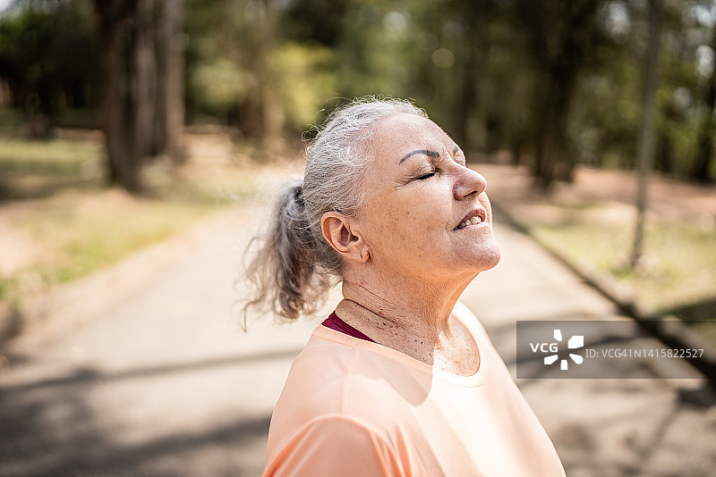 在公园里闭目深呼吸的老年妇女图片素材