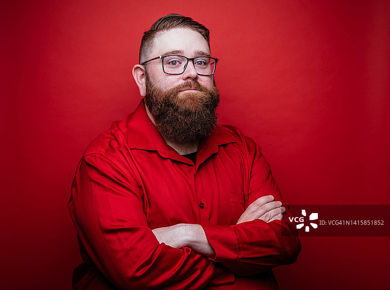 红色背景上表情严肃的络腮胡男子图片素材