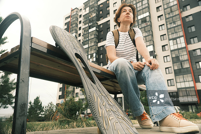 女人坐在长椅上休息滑板图片素材