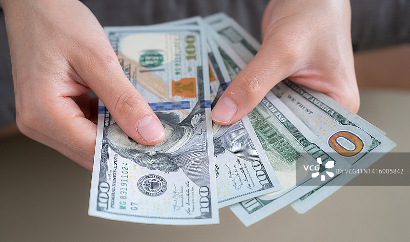某人手中拿着并数着美元纸币的特写图片素材