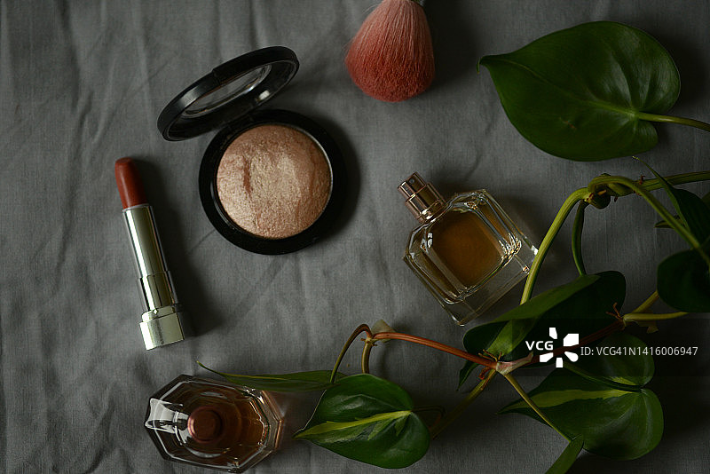 两瓶香水、红色口红和高光笔，深色背景图片素材