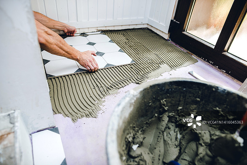 男人在家DIY装修，铺设瓷砖地板图片素材