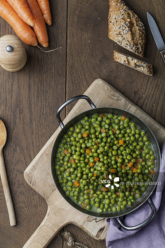棕色木制厨房台面上平底锅里的绿豌豆图片素材