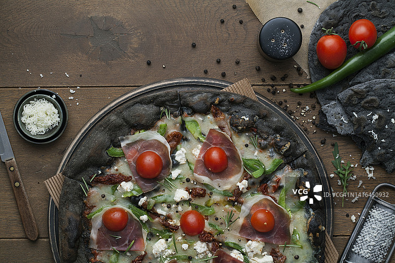 深色披萨配火腿、奶酪、青椒和圣女果图片素材
