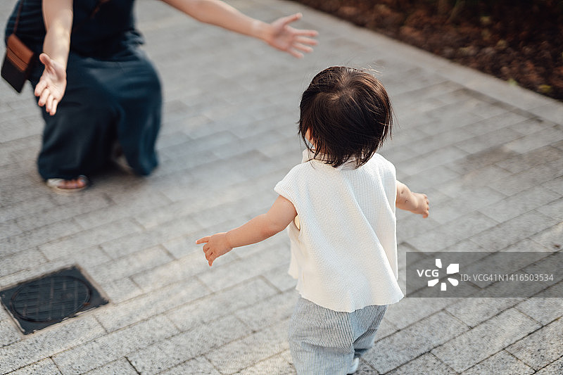 可爱的亚洲幼儿跑向母亲的背影图片素材