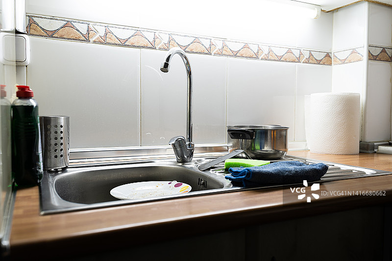 凌乱的水槽和堆满盘子的小厨房图片素材