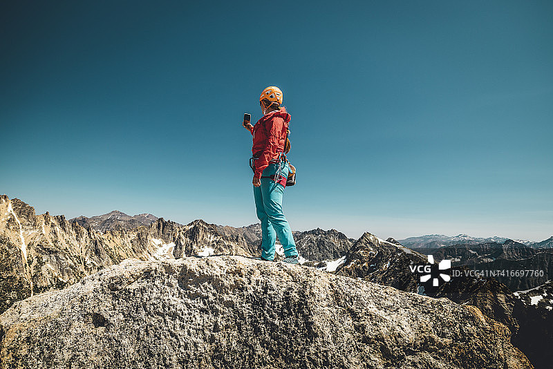 女子站在山顶上用手机拍照图片素材