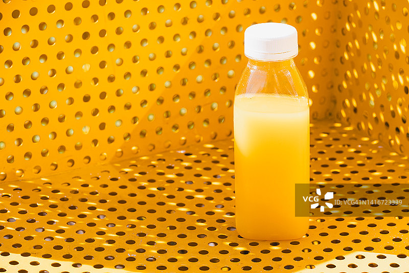 黄色背景下的橙汁塑料瓶图片素材