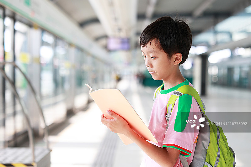 拿着书等待地铁的男孩图片素材