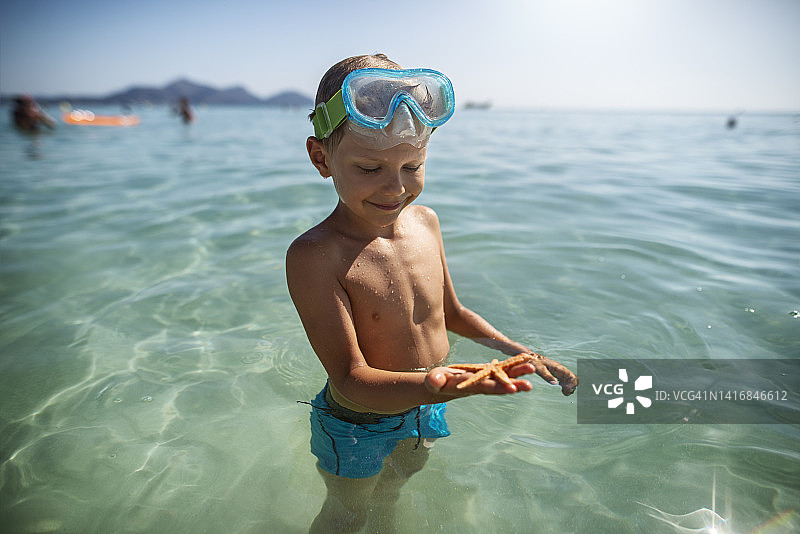 可爱的小男孩拿着海星图片素材