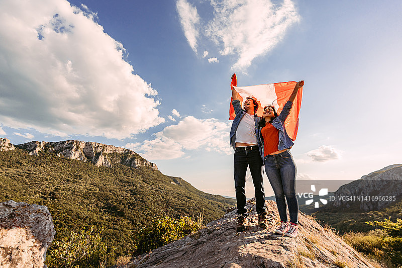 年轻夫妇在山顶挥舞加拿大国旗图片素材