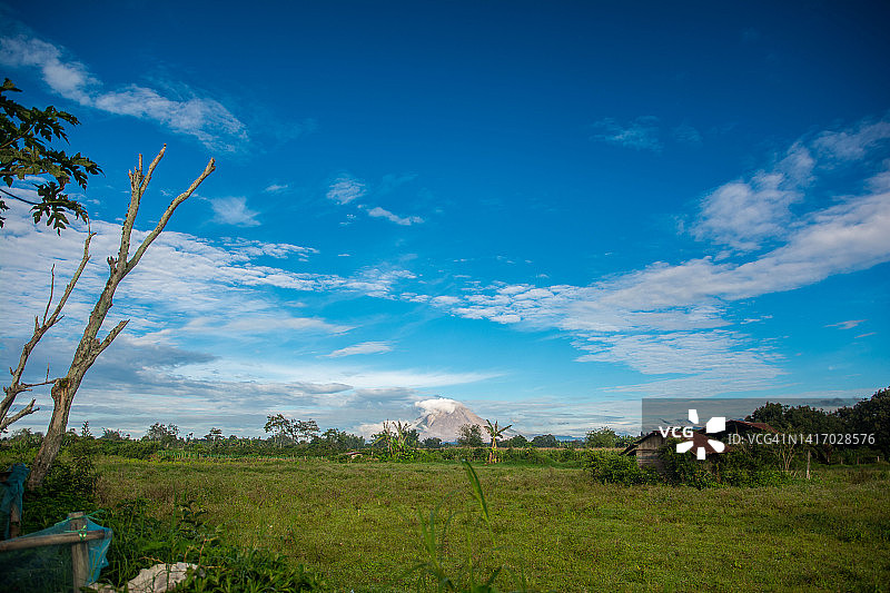 绿色草甸和蓝天，以锡纳朋火山为背景图片素材