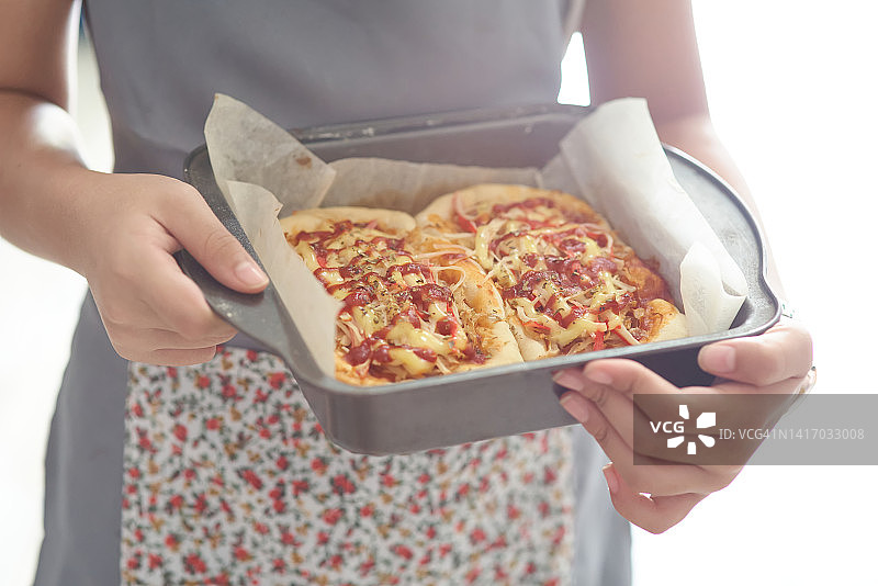 厨师手托披萨烤盘的局部照图片素材