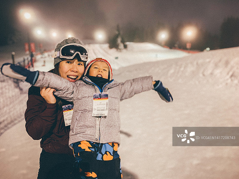 圣诞节期间在加拿大惠斯勒与母亲一起玩雪上运动的男孩图片素材