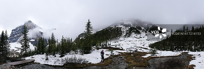 徒步登山的妇女欣赏白雪皑皑的山脉图片素材