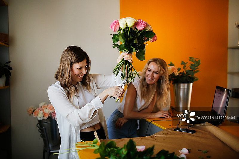花店里的两个年轻女合伙人制作花束并做生意图片素材