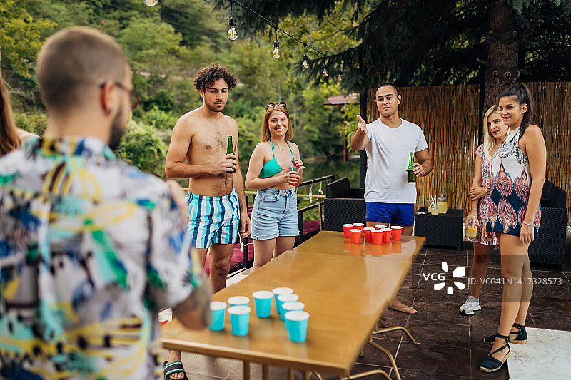 一群快乐的朋友在泳池派对上一起玩有趣的饮酒游戏图片素材