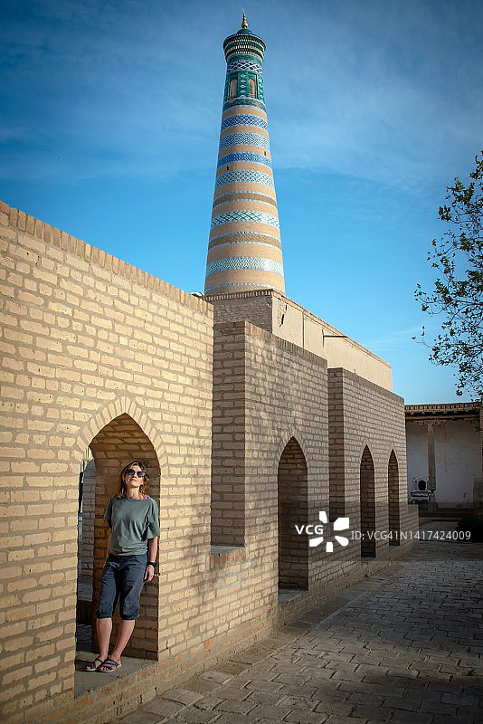 在乌兹别克斯坦希瓦伊钦卡拉的伊斯兰霍贾宣礼塔附近旅行的女人图片素材