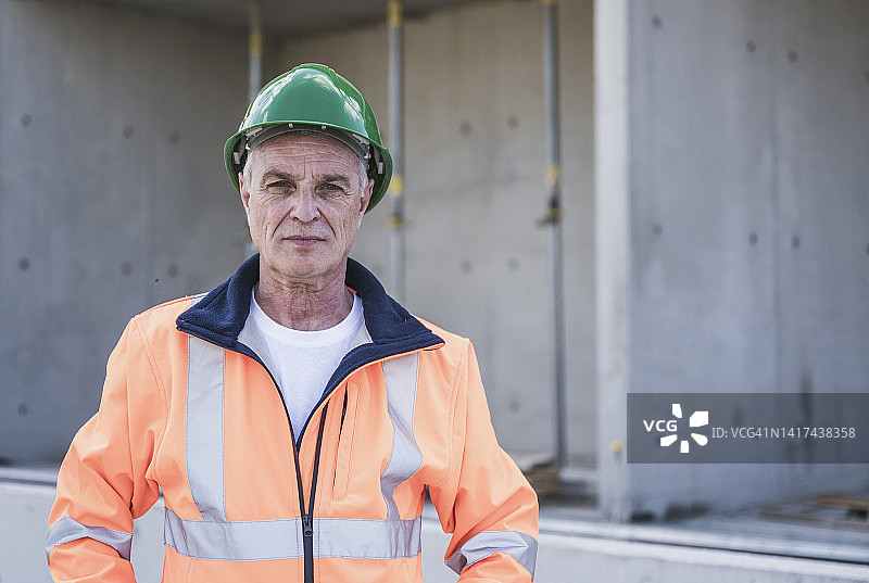 自信的建筑工人在建筑工地穿着反光服和安全帽图片素材
