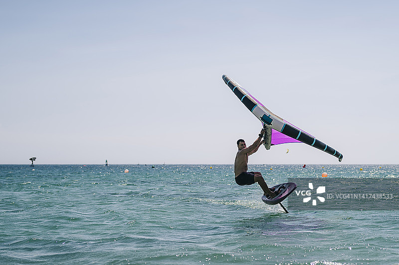 年轻男人在海上练习风翼图片素材