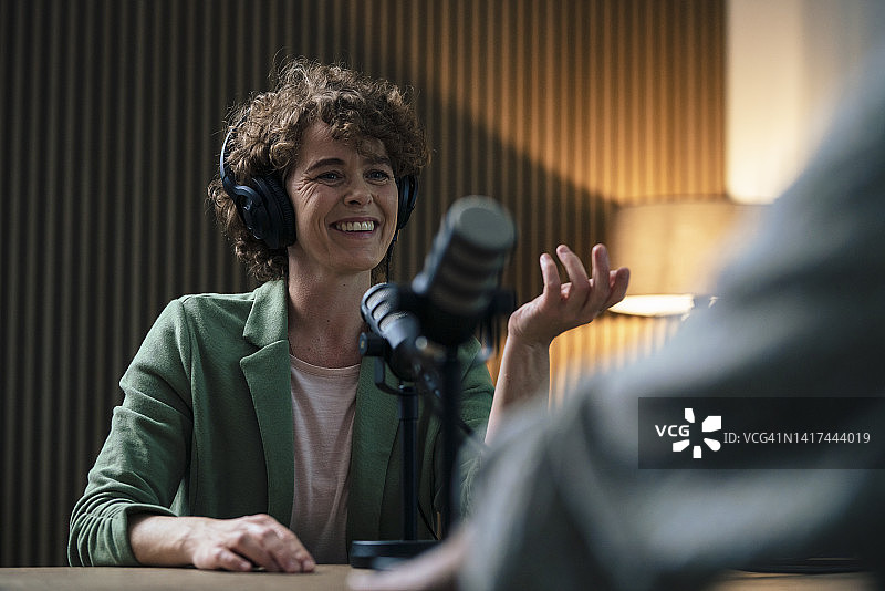 快乐的主持人在录音室与嘉宾交谈图片素材