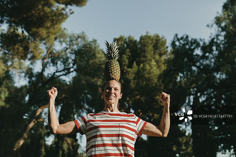在公园里头顶菠萝并展示肌肉的女人图片素材