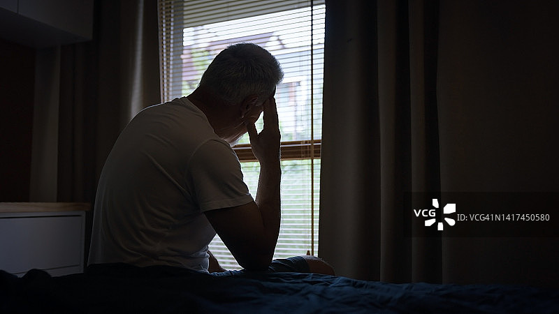 疲惫、沮丧的成熟男人清晨起床，双手捂头图片素材