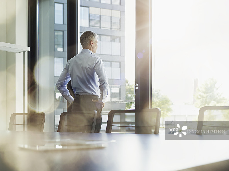在会议室里透过窗户向外看的商人图片素材