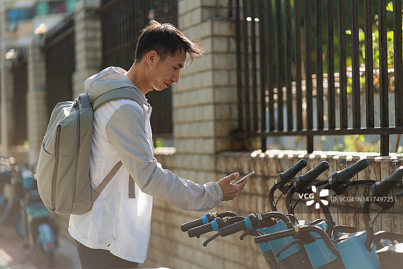 男子使用手机支付共享电动汽车费用图片素材