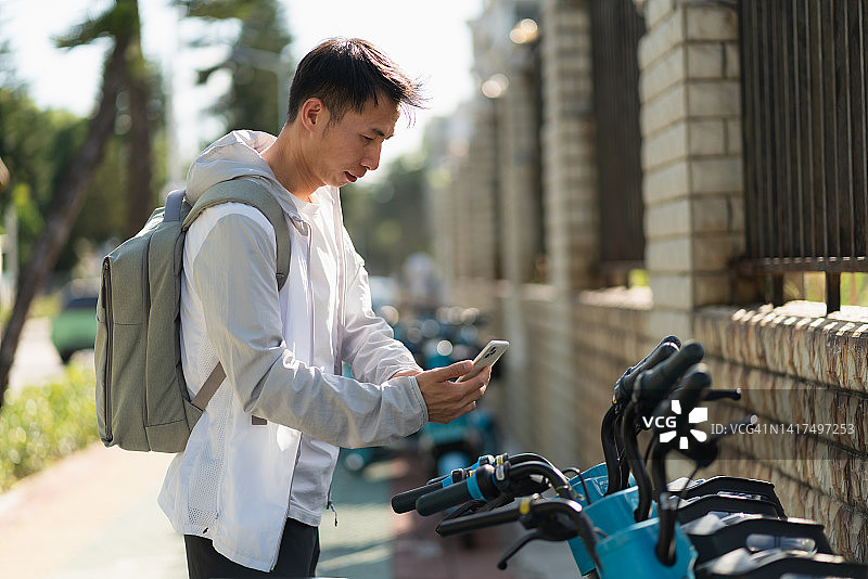 男子使用手机支付共享电动汽车费用图片素材