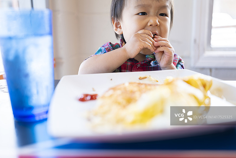 在自助餐厅吃鸡蛋菜肴的亚洲男孩图片素材